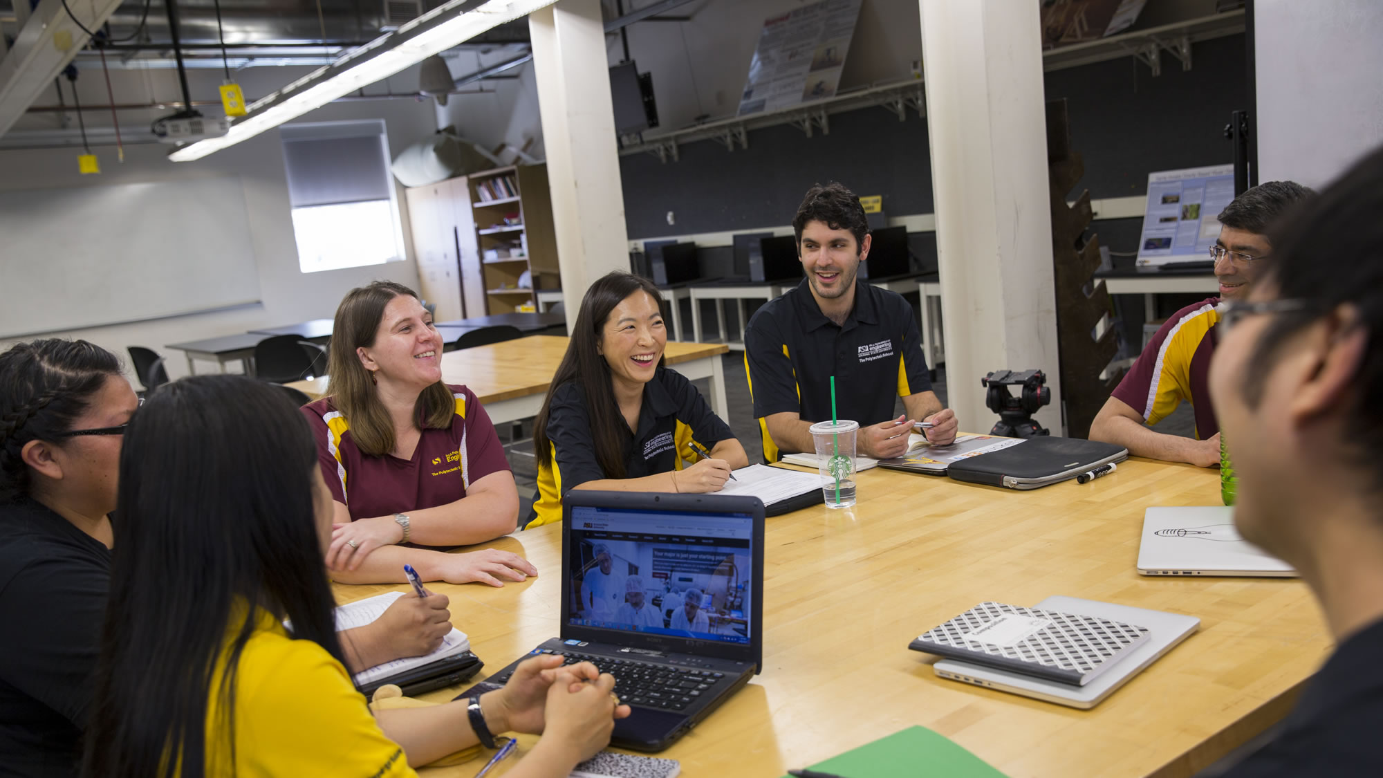 A group of faculty members gather at a table having a pleasant discussion